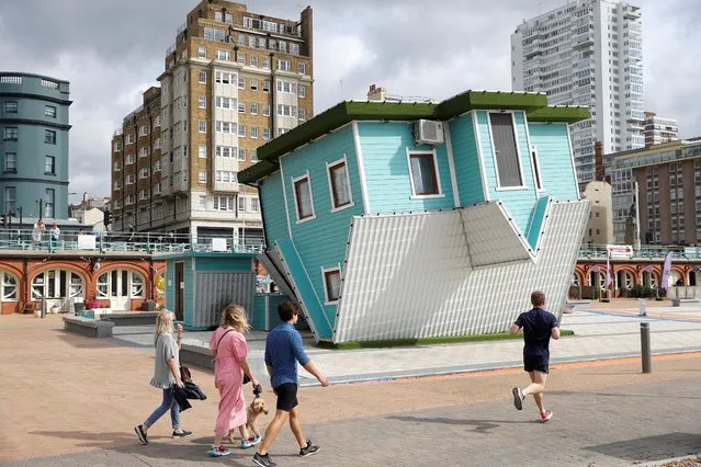 People walk past the Upside Down House attraction next to the beach in Brighton, Britain, September 12, 2020. (Photo by Peter Nicholls/Reuters)