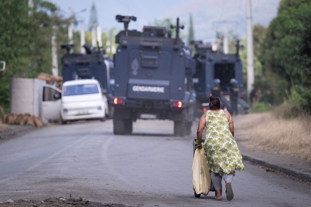A pedestrian walks near a French gendarmerie roadblock in Saint Louis on the way to Mont-Dore, in France's Pacific territory of New Caledonia, on September 23, 2024. French authorities on September 19, grappled with a new spike in violence in the country's overseas territories with security forces killing two men in New Caledonia and officials ordering a curfew after rioting in Martinique. (Photo by Sebastien Bozon/AFP Photo)