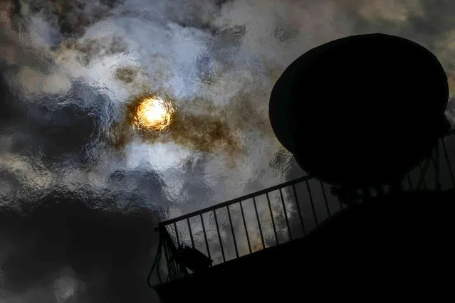 The sun is seen trough the flame of a gas torch lit on top of a Rostral column during celebrations for the 320th anniversary of St. Petersburg, in St. Petersburg, Russia, Saturday, May 27, 2023. (Photo by Dmitri Lovetsky/AP Photo)