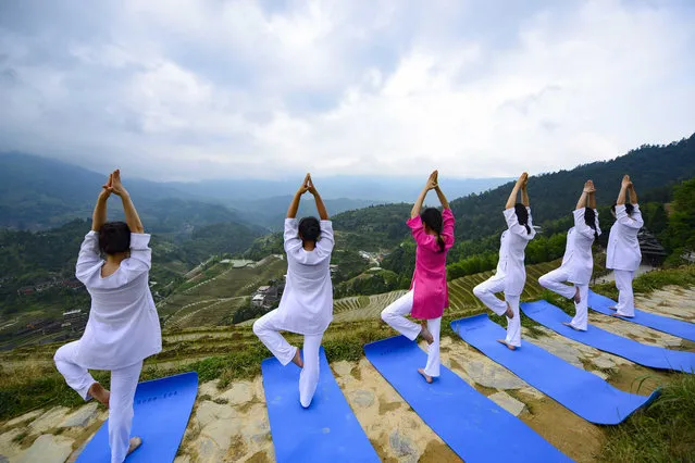 People practice yoga by the Longji terrace fields in Longsheng County, south China's Guangxi Zhuang Autonomous Region, June 21, 2018. The UN General Assembly declared June 21 as the International Yoga Day in 2014. (Xinhua/Pan Zhixiang via Getty Images)