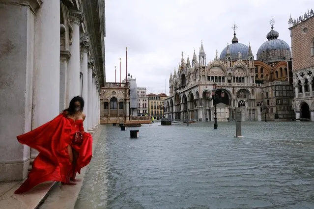 A woman stands in flooded St. Mark's Square during high tide as the flood barriers known as Mose are not raised, in Venice, Italy, December 8, 2020. The system of 78 flood gates, known as Mose, guard the entrance to the Venetian lagoon and are designed to protect the city from tides of up to 10ft (3 metres). However, they require 48-hours notice to be activated. (Photo by Manuel Silvestri/Reuters)