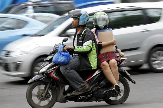 A woman rides on the back of a motorbike, part of the GrabBike ride-hailing service, on a busy street in central Jakarta, Indonesia December 18, 2015. Indonesia's president publicly rebuked one of his cabinet ministers on Friday for a clampdown on ride-hailing services such as Uber and Go-Jek, which triggered outrage on social media in a country where public transport options are limited. (Photo by Garry Lotulung/Reuters)