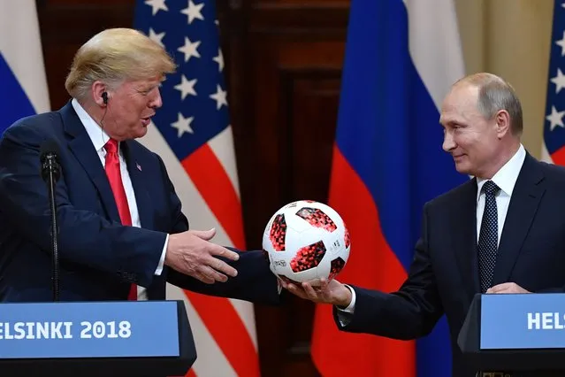 Russia's President Vladimir Putin offers a ball of the 2018 football World Cup to US President Donald Trump during a joint press conference after a meeting at the Presidential Palace in Helsinki, on July 16, 2018. (Photo by Yuri Kadobnov/AFP Photo)