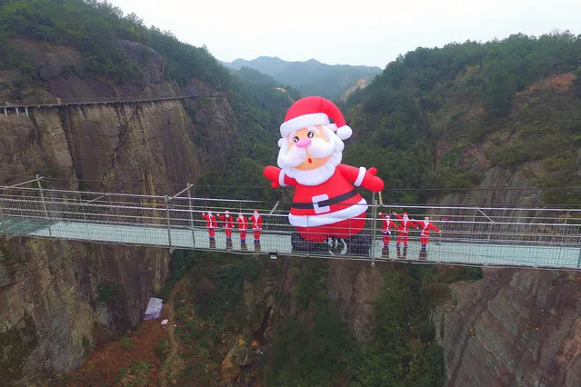 Tourists look at a 10-meter-tall Santa Claus on the 180-meter-high and 300 meter-long glass-bottomed suspension bridge at the Shiniuzhai National Geopark in Pingjiang county. A 10-meter-tall Santa Claus appeared on the 180-meter-high glass-bottomed suspension bridge that sits 180 meters above the ground at the Shiniuzhai National Geopark in Pingjiang county, in central China's Hunan province on Wednesday, December 23, 2015. (Photo by Imaginechina/Splash News)
