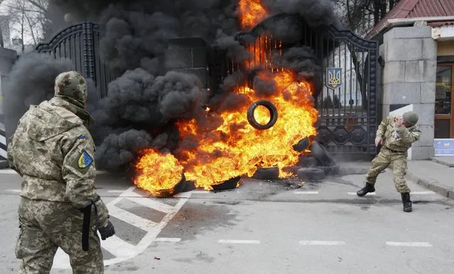 A serviceman from the battalion “Aydar” throws a tyre on a fire during a protest against disbanding of the battalion in front of Ukraine's Defence Ministry in Kiev, February 2, 2015. (Photo by Valentyn Ogirenko/Reuters)
