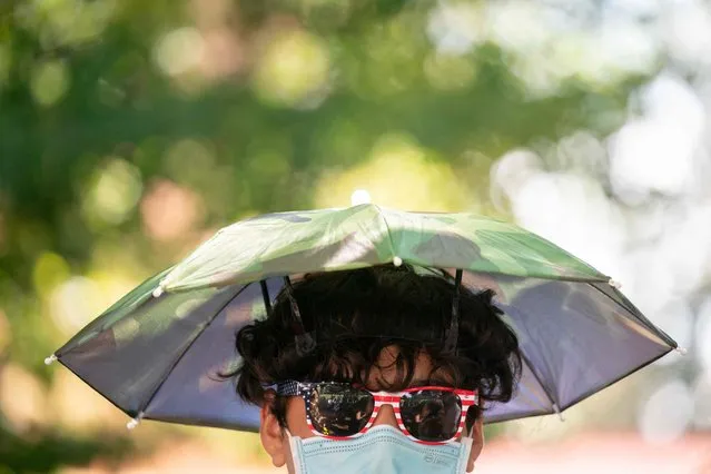 A person wears US flag sunglasses while shading themselves from the sun on Independence Day at George Washington's Mount Vernon in Mount Vernon, Virginia, on July 4, 2023. (Photo by Stefani Reynolds/AFP Photo)