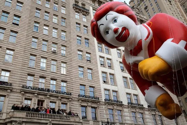 People watch from their balcony as the Ronald McDonald balloon is carried down Central Park West during the 90th Macy's Thanksgiving Day Parade in Manhattan, New York, U.S., November 24, 2016. (Photo by Andrew Kelly/Reuters)