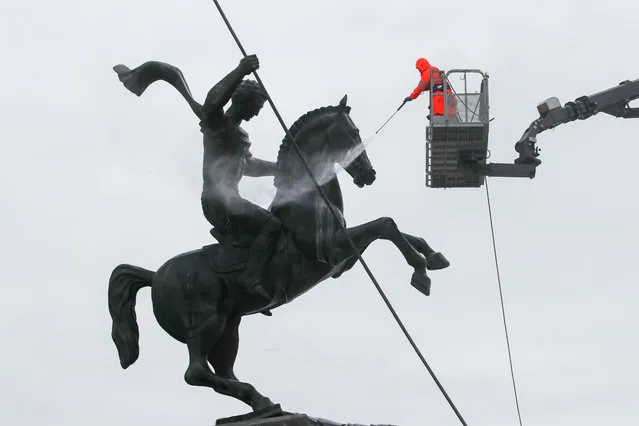 A Gormost worker power washes an equestrian statue of St George at the Victory monument during spring cleaning at the WWII memorial on Poklonnaya Gora in Moscow, Russia on March 17, 2021. (Photo by Sergei Karpukhin/TASS)