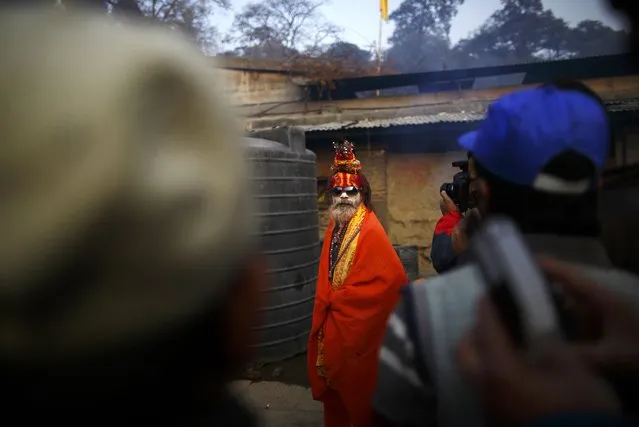 Devotees gather around a Hindu holy man, or sadhu, smeared with ashes at the premises of Pashupatinath Temple in Kathmandu February 16, 2015. Hindu holy men from Nepal and India come to this temple to take part in the Maha Shivaratri festival. Celebrated by Hindu devotees all over the world, Shivaratri is dedicated to Lord Shiva, and holy men mark the occasion by praying, smoking marijuana or smearing their bodies with ashes. (Photo by Navesh Chitrakar/Reuters)