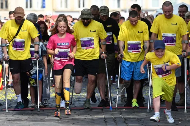 Yana Stepanenko, 12, (2ndL) and Ukrainian servicemen with limb loss take part in a half marathon in the western Ukrainian city of Lviv on September 3, 2023. (Photo by Yuriy Dyachyshyn/AFP Photo)