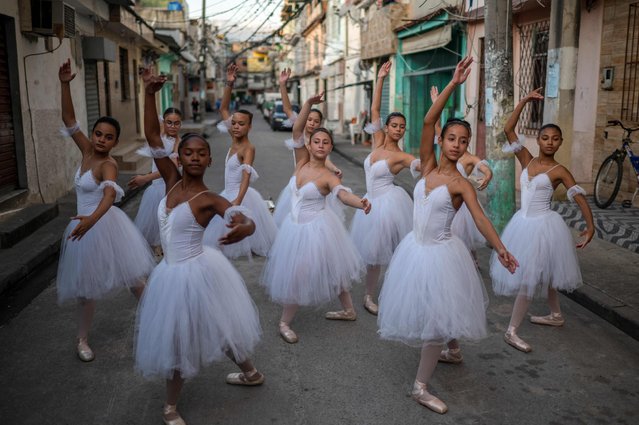 Students of the Ballet Manguinhos School practice dance movements after a photo session at the Manguinhos favela in Rio de Janeiro, Brazil, on June 27, 2022. About 400 students between six and 29 years old take free dance classes in Ballet Manguinhos – a kind of oasis in a neighbourhood that lives under the sway of drug trafficking and where classes are regularly interrupted by shootings during police operations – and which is now facing the possibility of closure due to financial difficulties. (Photo by Mauro Pimentel/AFP Photo)