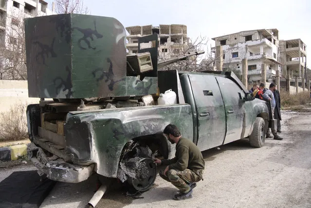 A Syrian soldier inspects a damaged pickup truck with a gun mounted on top in Salma, Syria, Friday, January 22, 2016. (Photo by Vladimir Isachenkov/AP Photo)