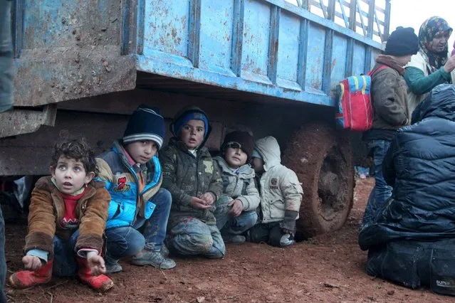 Displaced children, who fled with their families the violence from Islamic State-controlled area of al-Bab, wait as they are stuck in the Syrian village of Akda to cross into Turkey, January 23, 2016. Turkey's border guards prevented the displaced people from approaching their country's border, activists said. (Photo by Abdalrhman Ismail/Reuters)