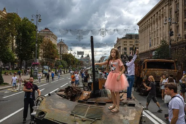 A girl stands on top of destroyed Russian military equipment at Khreshchatyk street in Kyiv on August 20, 2022, that has been turned into an open-air military museum ahead of Ukraine's Independence Day on August 24, amid Russia's invasion of Ukraine. (Photo by Dimitar Dilkoff/AFP Photo)
