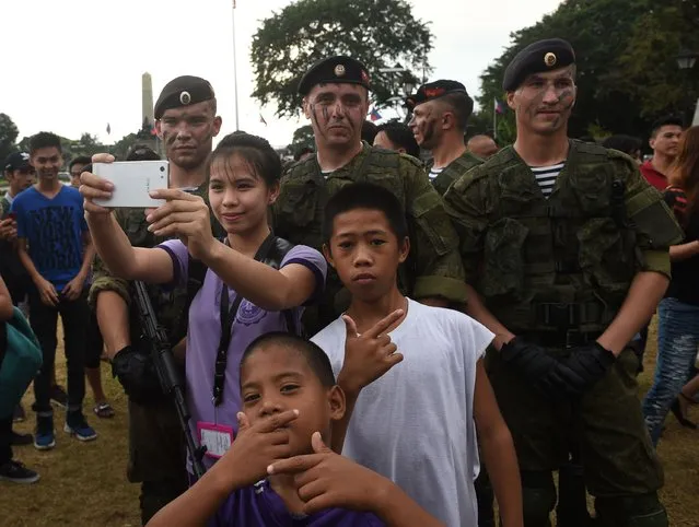 Russian marines attached to the anti- submarine ship Admiral Tributs pose for photos with Filipinos during a demonstration at a park in Manila on January 5, 2017, as part of their five- day port- of- call activities in the country' s capital. (Photo by Ted Aljibe/AFP Photo)