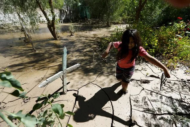 A child wades through the mud next to a grave inside the flooded cemetery in Los Loros town, April 7, 2015. The death toll from heavy rains and flooding that battered Chile last week has risen to 29, with another 150 still missing, according to authorities. (Photo by Ivan Alvarado/Reuters)