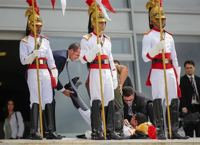 A member of Brazil's presidential guard is attended to after fainting during a welcome ceremony for France's President Francois Hollande at the Planalto Palace in Brazil, on December 12, 2013. (Photo by Ueslei Marcelino/Reuters)