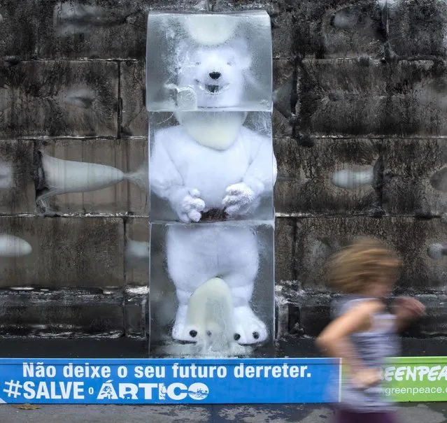 A polar bear replica, which is displayed by Greenpeace activists, is seen inside a block of ice in reference to the melting ice in the Arctic region, at Paulista avenue in Sao Paulo December 18, 2013. The sign reads “Do not let your future melt. Save the Arctic”. (Photo by Rodrigo Paiva/Reuters)