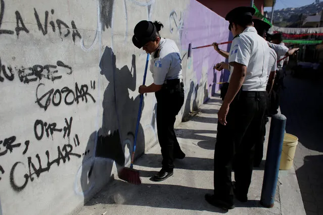 A policewoman sweeps the floor as fellow policemen erase graffities associated with the Mara Salvatrucha gang during an operation aimed to erase gang-related graffiti at the El Bucaro settlement in Guatemala City, Guatemala January 20, 2017. (Photo by Luis Echeverria/Reuters)