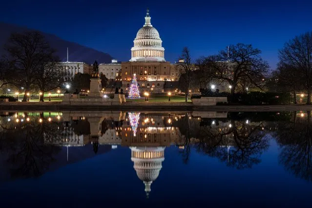 The U.S. Capitol building and the Capitol Christmas Tree are mirrored in the still waters of the Lincoln Memorial Reflecting Pool early Christmas morning, Monday, December 25, 2023, in Washington. (Photo by J. David Ake/AP Photo)