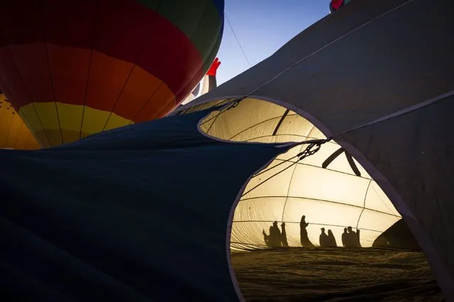 People cast shadows as they walk by a hot air balloon during the Albuquerque International Balloon Fiesta in Albuquerque, New Mexico, on Friday, October 13, 2023. (Photo by Chancey Bush/Albuquerque Journal/Zuma Press)