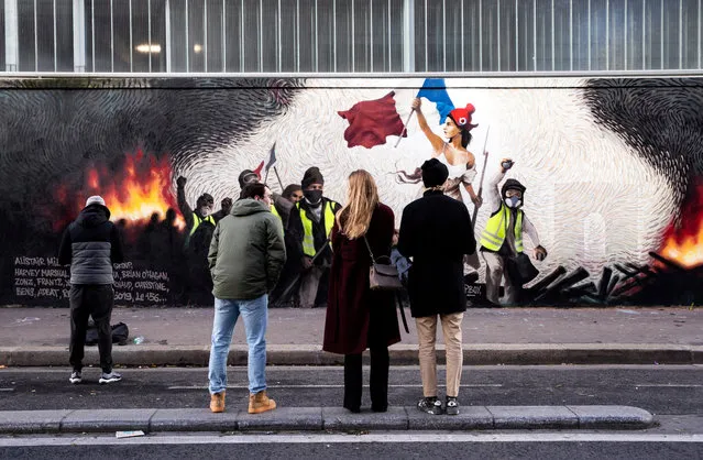 People look for clues to get a reward hidden in a mural reproducing a “Yellow Vests” version of Eugene Delacroix “Liberty Leading the People” by French crypto-artist Pascal Boyart in Paris, France, 08 January 2019. The artist hid clues leading to a digital wallet containing 0,26 Bitcoin around 900€. (Photo by Etienne Laurent/EPA/EFE)