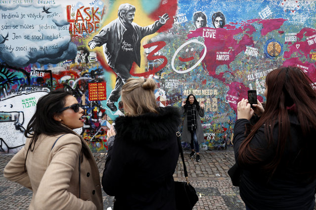 Tourists pose for a photo by newly created graffiti of Czech Republic's late President Vaclav Havel that dominates the Prague's famous “Lennon Wall”, in Prague, Czech Republic, Tuesday, March 19, 2019. Around 20 artists repainted and resprayed the Prague's colorful wall, that is dedicated to the memory of John Lennon, to mark the 30th anniversary of the 1989 anti-communist Velvet Revolution. Under the communist regime, the wall became a symbol of freedom and opposition to communism, now it's a tourist attraction. (Photo by Petr David Josek/AP Photo)