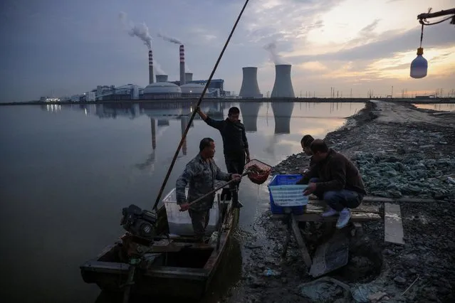 Fishermen bring in their catch from a lake in front of a power plant of the State Development and Investment Corporation (SDIC) outside Tianjin, China, October 14, 2021. (Photo by Thomas Peter/Reuters)