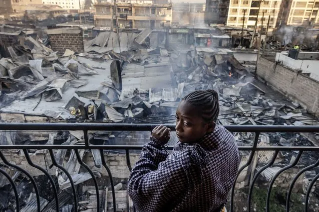 A woman looks from a balcony at the heavily damaged houses and shops, a day after a gas explosion in the Embakasi area of Nairobi, on February 2, 2024. At least three people were killed and more than 270 injured in a massive fire when a truck laden with gas exploded in the Kenyan capital. Firefighters managed to bring the blaze under control by around 9:00 am (0600 GMT), more than nine hours after it erupted, according to an AFP journalist at the scene. (Photo by Luis Tato/AFP Photo)