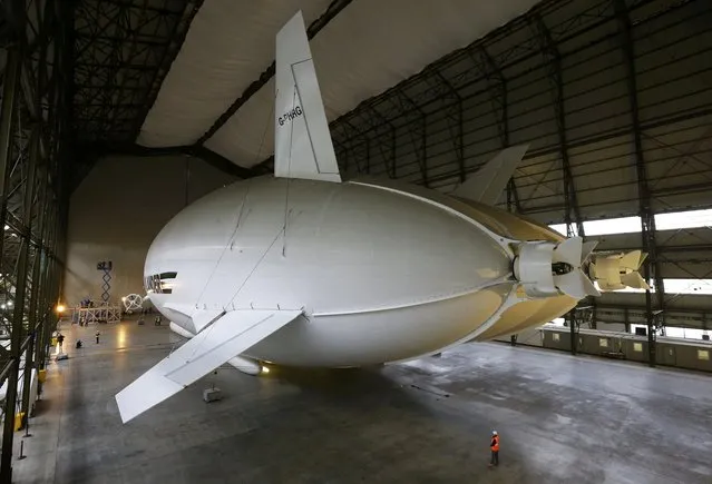 A worker stands under the Airlander 10 hybrid airship during its unveiling in Cardington, Britain March 21, 2016. (Photo by Darren Staples/Reuters)