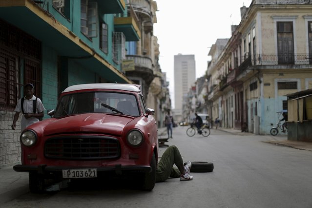 A man repairs a vintage car on a street in Havana, Cuba March 21, 2016. (Photo by Ueslei Marcelino/Reuters)