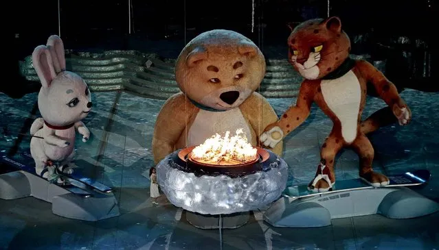 A large mascot gets ready to blow out the Olympic flame. (Photo by Ivan Sekretarev/Associated Press)