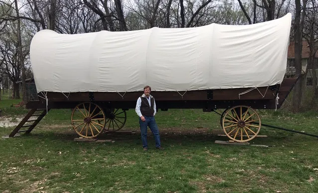 In this April, 11, 2019 photo, Dennis Steinman stands in front of his first covered wagon outside his home in rural Douglas County, Kansas. Dennis and Donna Steinman have built the first of what they hope will be many 26-by-10-foot canvas-covered wagons. Their PlainsCraft Conestoga Wagons are more like the Winnebago of covered wagons; they're intended for those drawn to glamorous camping, or glamping. (Photo by Kathy Hanks/Lawrence Journal-World via AP Photo)