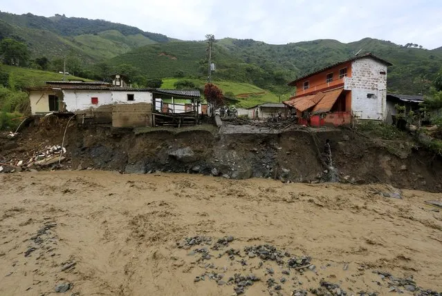 Partially destroyed houses are seen alongside La Liboriana river where a landslide sent mud and water crashing onto homes close to the municipality of Salgar in Antioquia department, Colombia May 19, 2015. (Photo by Jose Miguel Gomez/Reuters)