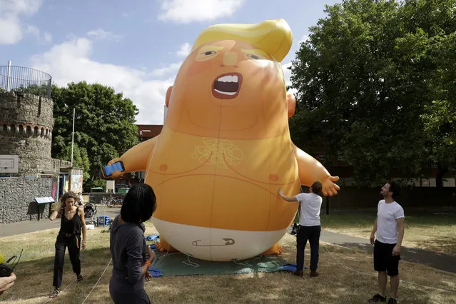 A six-meter high cartoon baby blimp of U.S. President Donald Trump stands inflated during a practice session in Bingfield Park, north London, 2018. Trump will get the red carpet treatment on his brief visit to England that begins Thursday: Military bands at a gala dinner, lunch with the prime minister at her country place, then tea with the queen at Windsor Castle before flying off to one of his golf clubs in Scotland. (Photo by Matt Dunham/AP Photo)