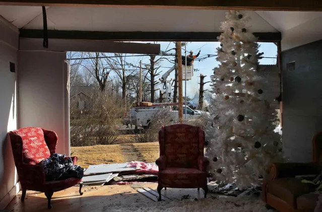 Utility crews from CenturyLink work to restore service outside a home where a Christmas tree stands in its living room at the corner of Highways F and 94 in Defiance, Mo. as cleanup continues from last Friday's tornado on Tuesday, December 14, 2021. (Photo by Robert Cohen/St. Louis Post-Dispatch via AP Photo)