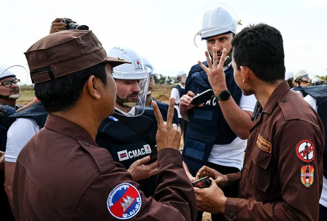 Ukraine deminers communicate with a Cambodian deminer at a mine field during a technical training session on demining technologies in Battambang province on January 19, 2023. (Photo by Tang Chhin Sothy/AFP Photo)
