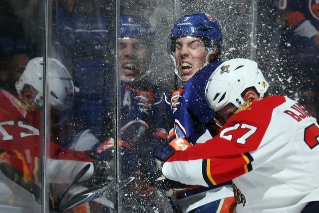 Travis Hamonic #3 of the New York Islanders is hit into the glass by Nick Bjugstad #27 of the Florida Panthers during the first period at the Nassau Veterans Memorial Coliseum on April 1, 2014 in Uniondale, New York. (Photo by Bruce Bennett/Getty Images)