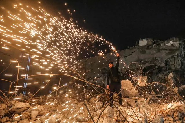 A man swings a homemade fireworks sparkler after sunset during the last night of the year in Gaza City on December 31, 2021. (Photo by Mahmud Hams/AFP Photo)