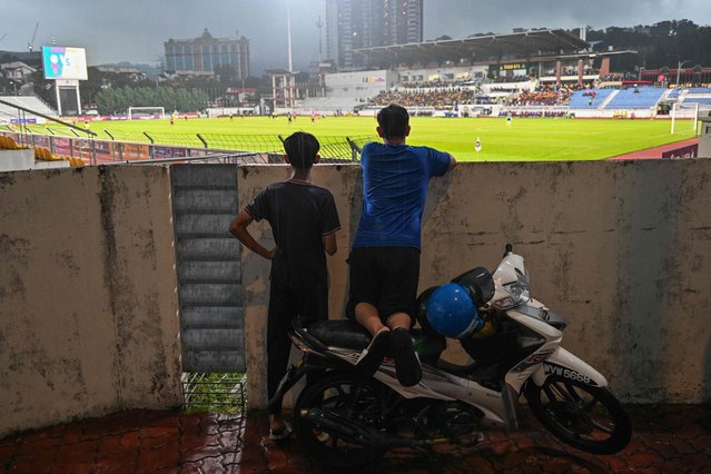 Two boys watch the Malaysia Super League game between Kedah Darul Aman Football Club and Polis DiRaja Malaysia Football Club in Kuala Lumpur on May 11, 2024. An unprecedented spate of attacks against footballers in Malaysia has left the country shocked and angry, prompting authorities to impose tighter security a few days before the super league season opens. (Photo by Mohd Rasfan/AFP Photo)