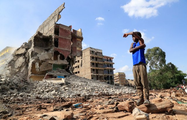 A boy looks at the search and rescue operations on the rubble of a residential flat built on riparian land, that collapsed while undergoing demolition near the Mathare River, in Mathare settlement of Nairobi, Kenya on May 14, 2024. (Photo by Thomas Mukoya/Reuters)