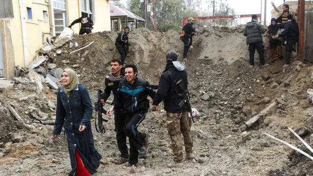 Iraqi security forces and Sunni tribal fighters help trapped civilians cross out of neighborhoods under Islamic State group control in Ramadi in this January 4, 2016, file photo. As they fled the city earlier this year, IS militants methodically destroyed buildings, infrastructure, bridges and dams in a scorched earth tactic that Iraq and U.S. officials fear they will use as they come under attack in other cities, particularly Mosul. (Photo by AP Photo)