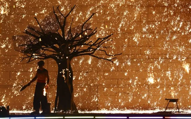 A Chinese blacksmith throws molten metal against a cold stone wall to create sparks during a summer carnival at Beijing World Park on August 7, 2019 in Beijing, China. (Photo by Zhao Jun/China News Service/VCG via Getty Images)