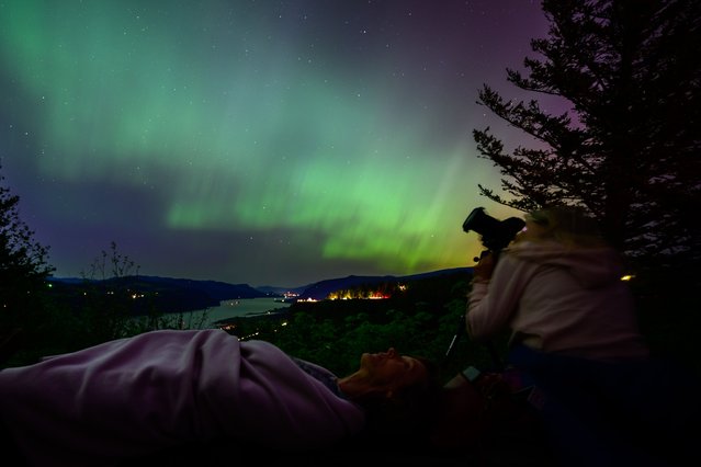 Kathryn Richer (left) and her friend Andrea gaze upon the Northern Lights at Chanticleer Point Lookout on the Columbia River Gorge in the early morning hours of May 11, 2024 in Latourell, Oregon. Places as far south as Alabama and parts of Northern California were expected to see the aurora borealis, also known as the northern lights from a powerful geomagnetic storm that reached Earth. (Photo by Mathieu Lewis-Rolland/Getty Images)