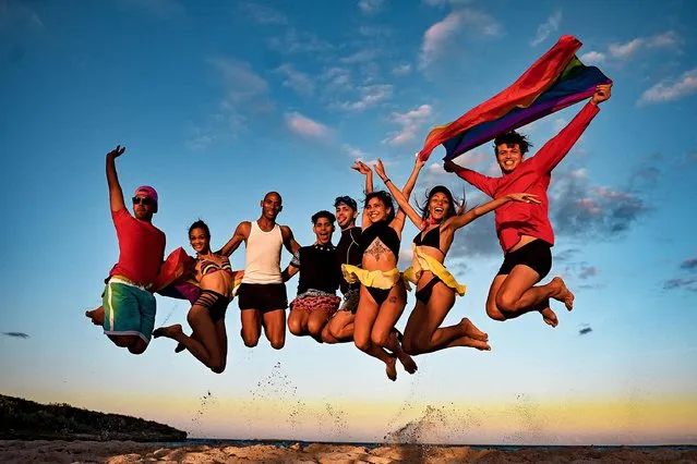 Cheerleading team jumps with LGBT flags at the Gran Muthu Rainbow Hotel, in Guillermo Key in Ciego de Avila Province, Cuba, on November 27, 2021. Cuba's first LGBT hotel, which had been inaugurated in December 2019, but very soon had to close due to the coronavirus pandemic, reopened to attract that tourist segment at a time when authorities are studying the approval of equal marriage on the island. Under all preventive sanitary measures, this five-star accommodation received its first clients again on November 15, when Cuba reopened its borders after 10 months of confinement. (Photo by Yamil Lage/AFP Photo)