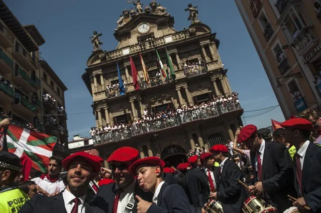 Members of the Gaiteros musician group gesture in front of the City hall, back, while celebrating during the launch of the “Chupinazo” rocket, to celebrate the official opening of the 2015 San Fermin Fiestas, in Pamplona, northern Spain, Monday, July 6, 2015. (Photo by Alvaro Barrientos/AP Photo)