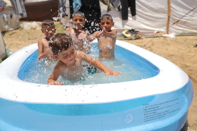 Palestinian children cool off inside an inflatable pool set up at the tent city amid Israeli attacks in Deir Al Balah, Gaza on June 18, 2024. (Photo by Hasan Jedi/Anadolu via Getty Images)