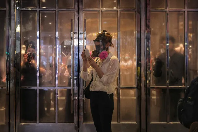 Bystanders looks at her mobile phone from a Victoria's Secret store as police fire tear gas to disperse protesters in Causeway Bay in Hong Kong on September 8, 2019.  Riot police on September 8 chased groups of hardcore protesters who blocked roads, vandalised nearby subway stations and set makeshift barricades on fire as the evening set in, while an earlier main daytime rally saw pro-democracy activists marching to the United States consulate in Hong Kong in a bid to ramp up international pressure on Beijing following three months of huge and sometimes violent protests. (Photo by Vivek Prakash/AFP Photo)