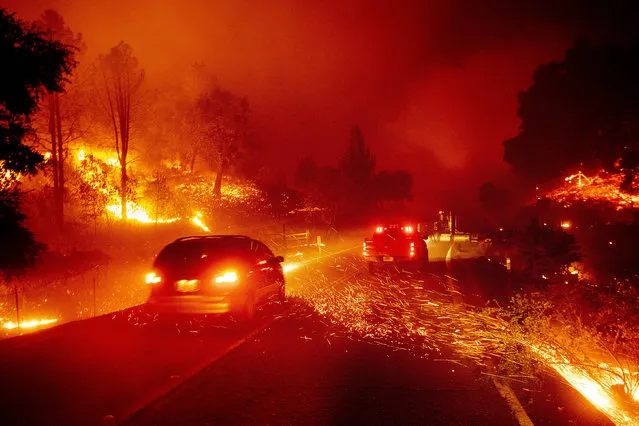Embers fly across a roadway as the Kincade Fire burns through the Jimtown community of Sonoma County, Calif., on Thursday, October 24, 2019. (Photo by Noah Berger/AP Photo)