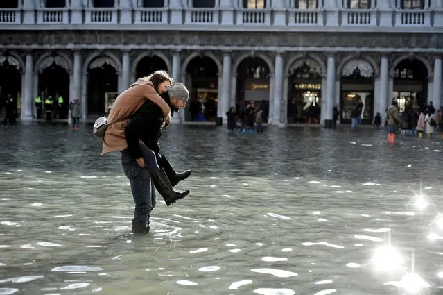 A man carries a woman on his back through the flooded St. Mark's Square during a period of seasonal high water in Venice, November 14, 2019. The Italian city has declared a state of emergency after “apocalyptic” floods swept through the lagoon city, flooding its historic basilica and inundating squares and centuries-old buildings. (Photo by Flavio Lo Scalzo/Reuters)